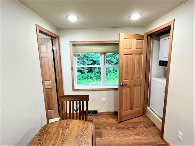 doorway to outside with stacked washer / dryer and wood finished floors