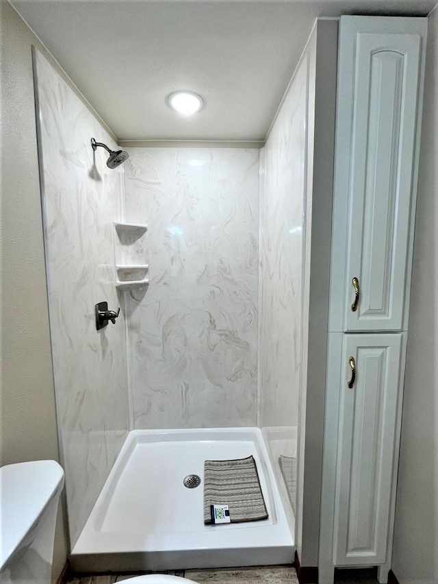 full bathroom featuring a stall shower and toilet