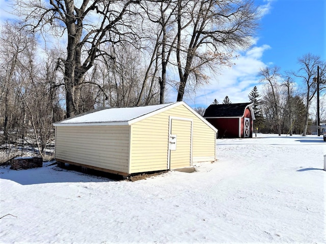 snow covered structure with a storage unit and an outbuilding