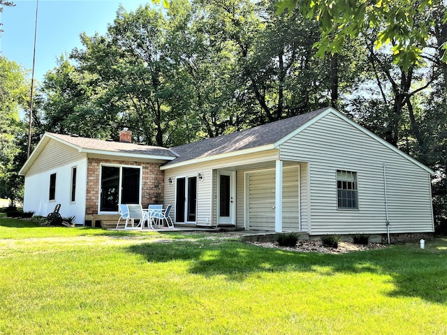 single story home featuring a front yard, a patio, and a chimney