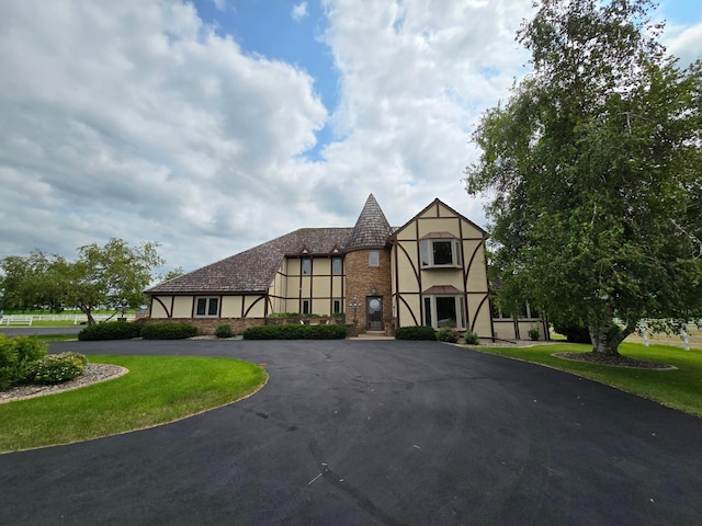 tudor-style house featuring a front lawn