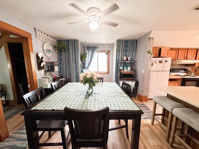 dining area with ceiling fan, a textured ceiling, and light wood-type flooring