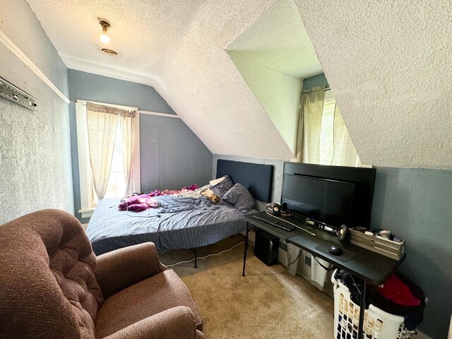 carpeted bedroom with a textured ceiling and vaulted ceiling