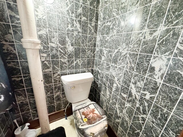 bathroom featuring tile walls and toilet