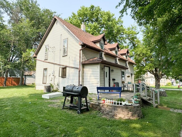 back of house with central AC unit and a yard