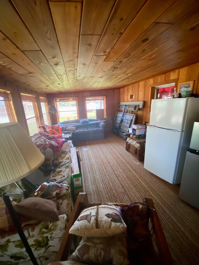 interior space with lofted ceiling, wood walls, wooden ceiling, and white fridge