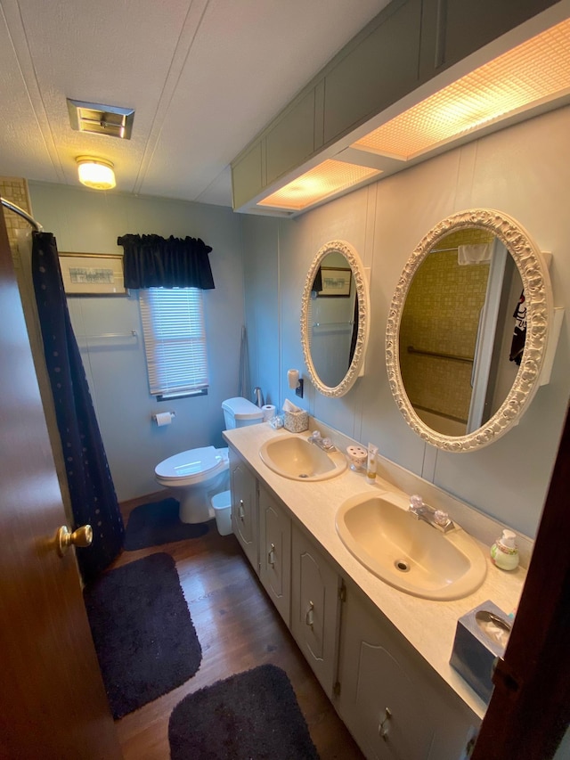 bathroom with hardwood / wood-style floors, toilet, and dual bowl vanity