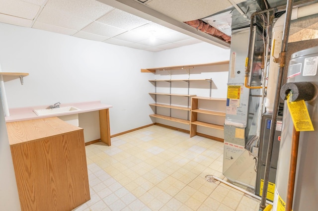 basement featuring sink, a drop ceiling, and heating unit