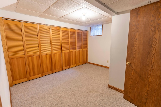 basement featuring light colored carpet and a paneled ceiling