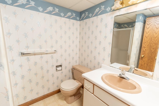 bathroom with a drop ceiling, toilet, walk in shower, and vanity