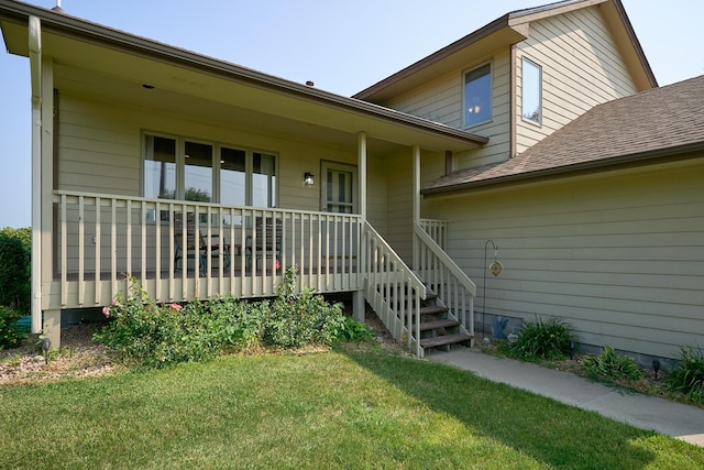 property entrance featuring a porch, a shingled roof, and a lawn