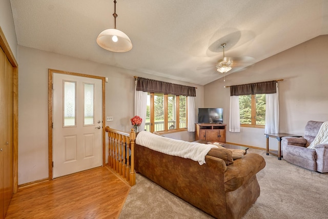 living room featuring vaulted ceiling, a ceiling fan, baseboards, and light wood-type flooring
