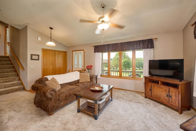living area featuring carpet floors, stairway, baseboards, a ceiling fan, and lofted ceiling