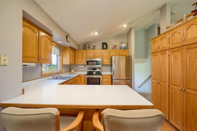 kitchen with stainless steel appliances, a sink, a peninsula, vaulted ceiling, and light countertops