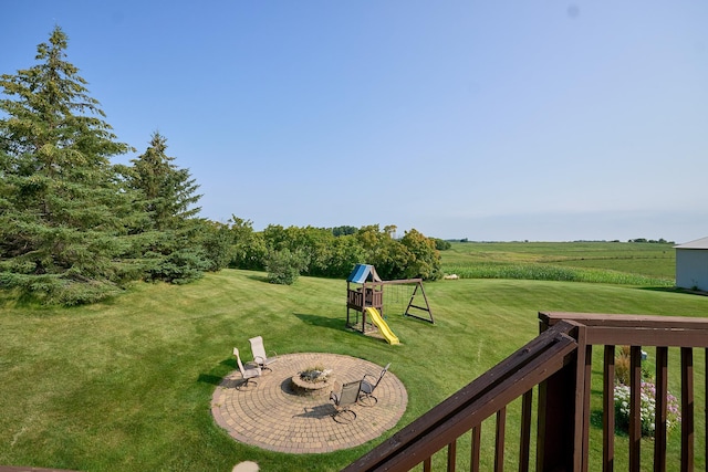view of green lawn with an outdoor fire pit and a playground