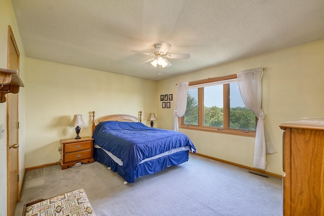 carpeted bedroom featuring baseboards, a ceiling fan, and a textured ceiling