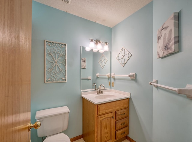 bathroom with toilet, a textured ceiling, vanity, and baseboards