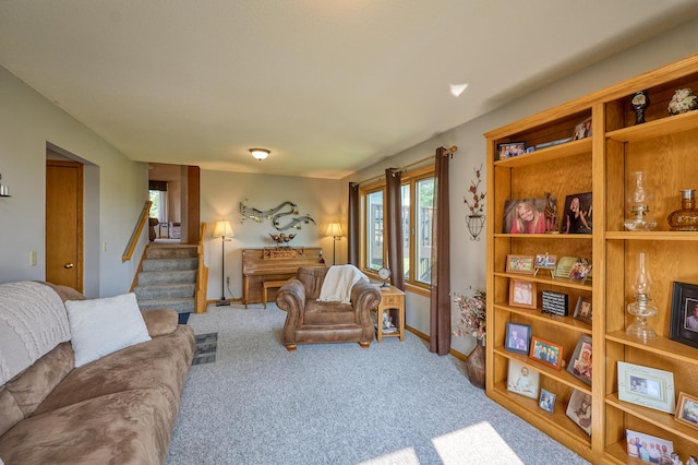 carpeted living area with stairway and baseboards
