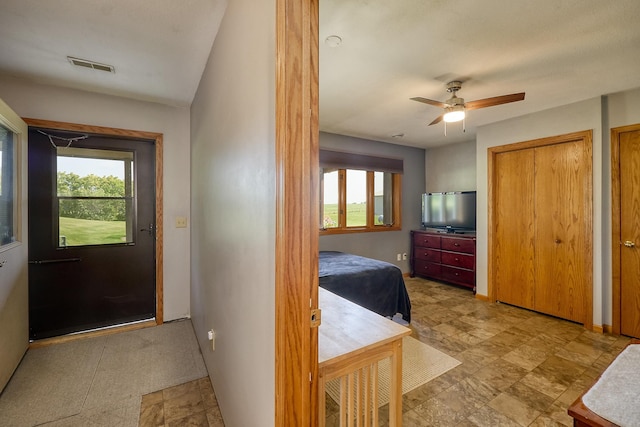 hall featuring healthy amount of natural light, light stone finish flooring, and baseboards
