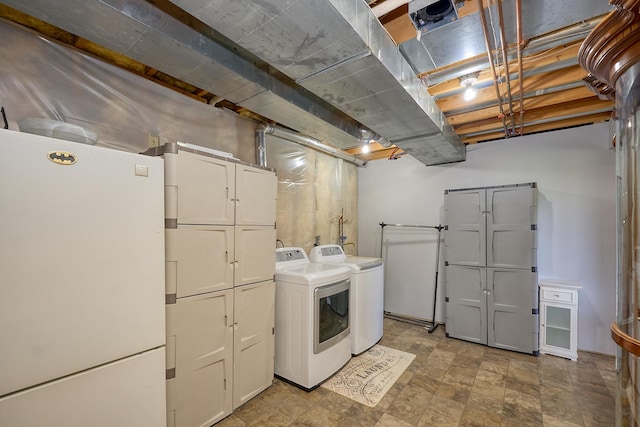 clothes washing area with cabinet space, washing machine and dryer, and stone finish floors