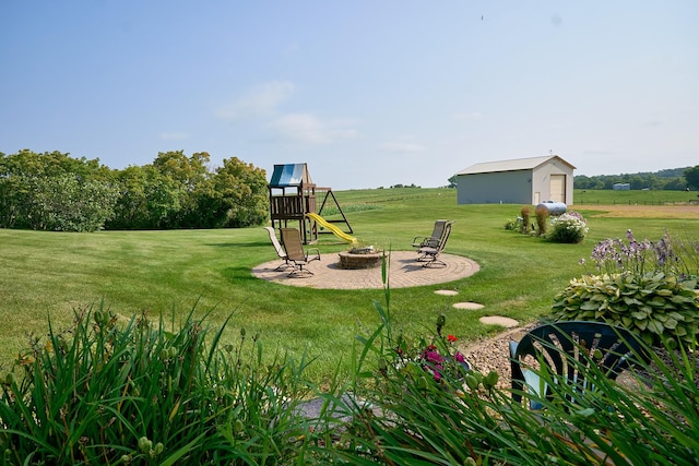 view of green lawn with an outdoor fire pit and an outbuilding