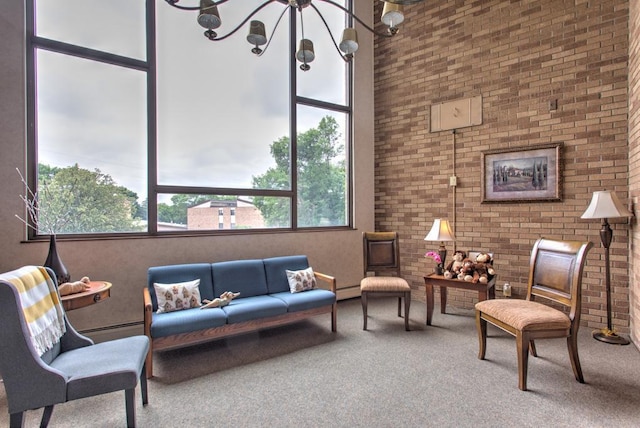 living room with carpet floors, a high ceiling, a baseboard heating unit, and a notable chandelier