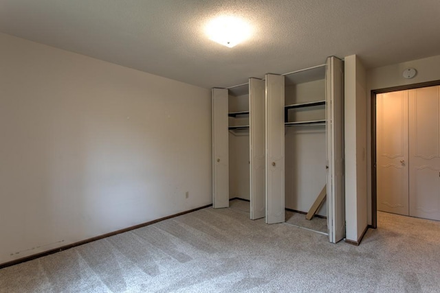 unfurnished bedroom with light carpet and multiple closets