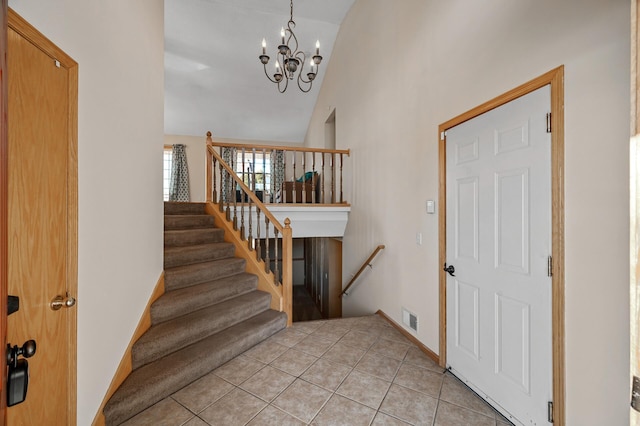 foyer with high vaulted ceiling, light tile patterned flooring, a notable chandelier, visible vents, and baseboards