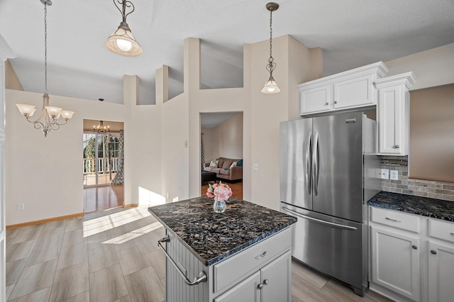 kitchen featuring vaulted ceiling, hanging light fixtures, freestanding refrigerator, and white cabinetry