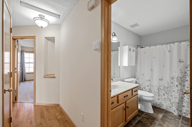 full bathroom featuring a textured ceiling, toilet, wood finished floors, visible vents, and vanity