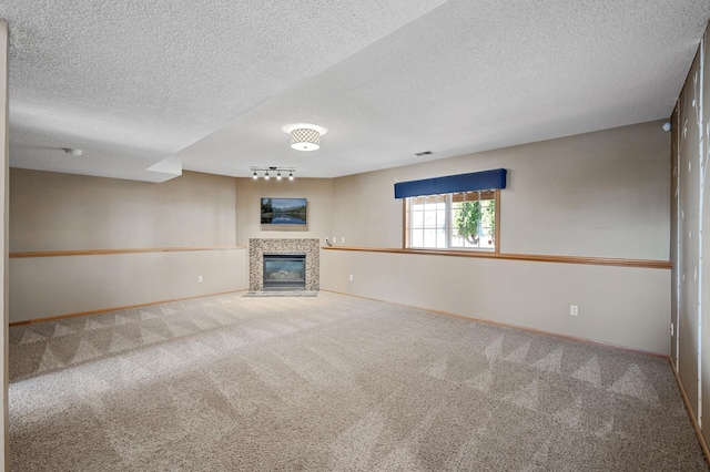 unfurnished living room with baseboards, visible vents, a tile fireplace, carpet, and a textured ceiling