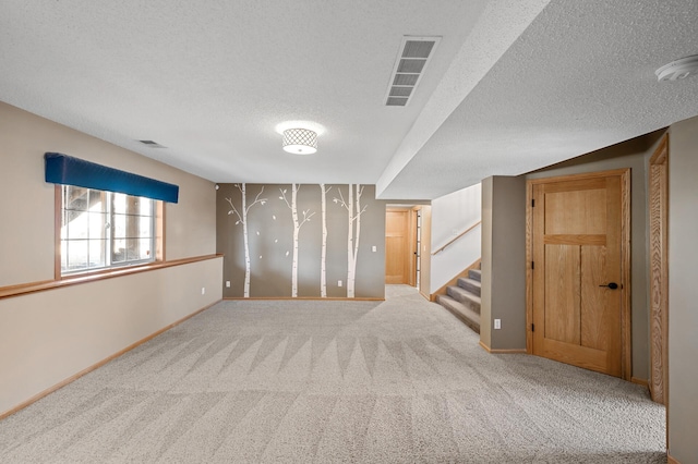 unfurnished room featuring stairway, a textured ceiling, visible vents, and carpet flooring