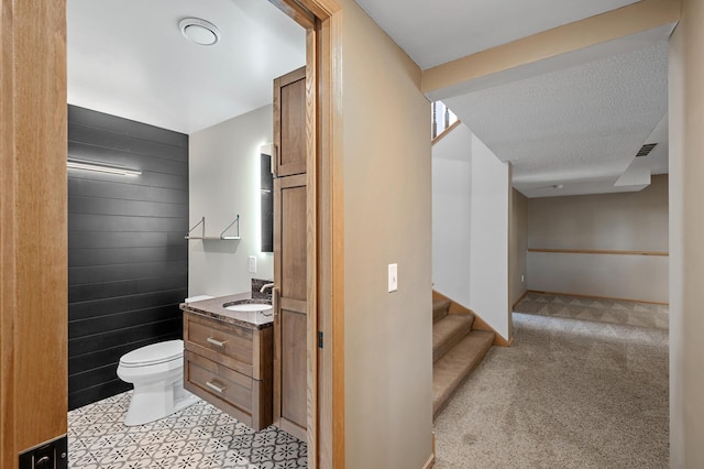 bathroom with wooden walls, visible vents, toilet, a textured ceiling, and vanity