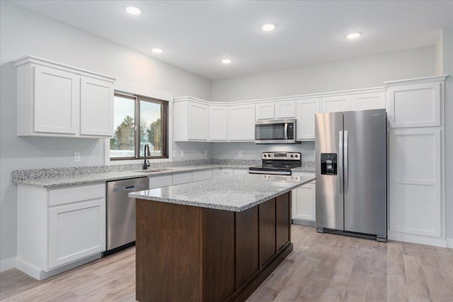 kitchen featuring a kitchen island, white cabinets, light wood-type flooring, and appliances with stainless steel finishes