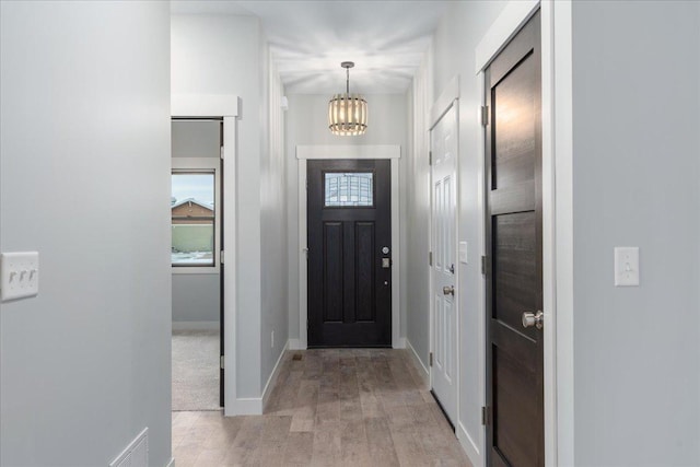 entryway with an inviting chandelier and light hardwood / wood-style flooring