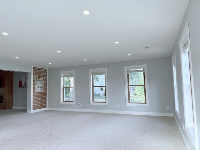 unfurnished room with light carpet and a fireplace