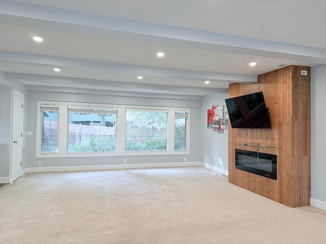 unfurnished living room featuring beamed ceiling, light colored carpet, and a fireplace