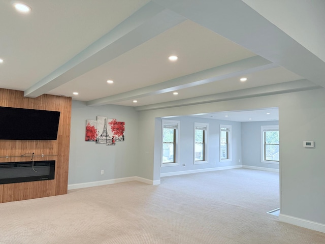 unfurnished living room featuring light carpet, a wealth of natural light, and beamed ceiling