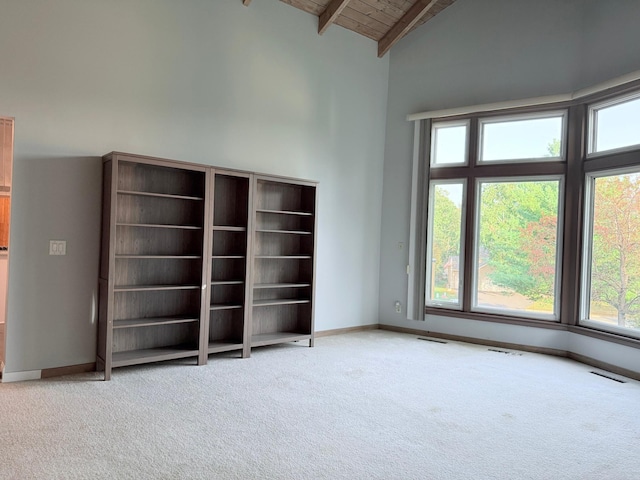 unfurnished living room with high vaulted ceiling, wood ceiling, beamed ceiling, and carpet flooring