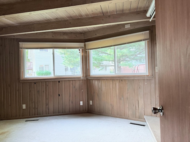 carpeted empty room with beamed ceiling, wood ceiling, and wood walls