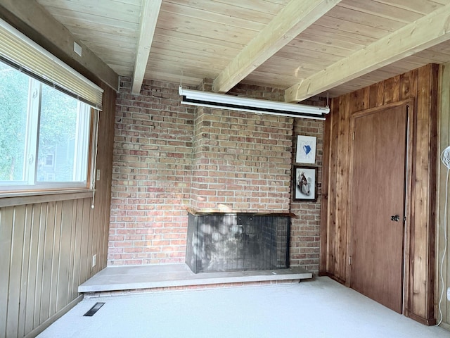 unfurnished living room with wood ceiling, wood walls, beam ceiling, and a fireplace