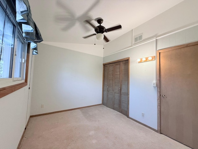 unfurnished bedroom with lofted ceiling, ceiling fan, light colored carpet, and a closet