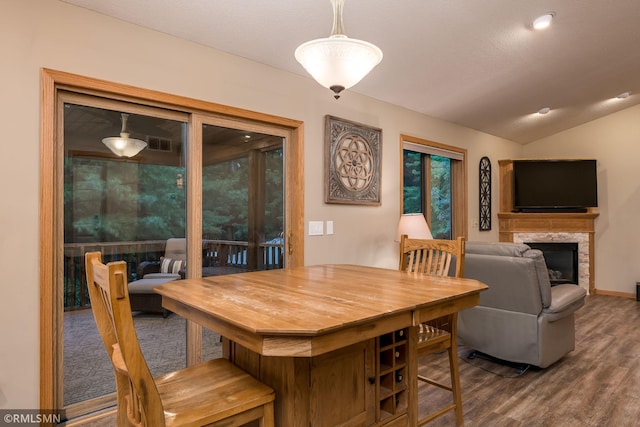 dining area with vaulted ceiling, a fireplace, and hardwood / wood-style floors