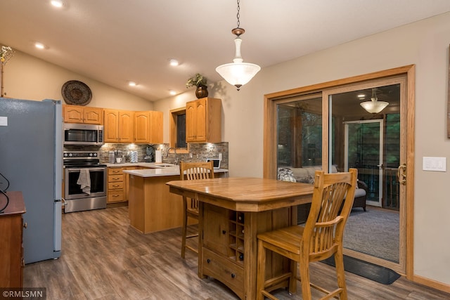 kitchen featuring stainless steel appliances, hanging light fixtures, dark wood-type flooring, and lofted ceiling