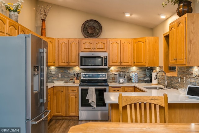 kitchen with sink, vaulted ceiling, kitchen peninsula, stainless steel appliances, and backsplash