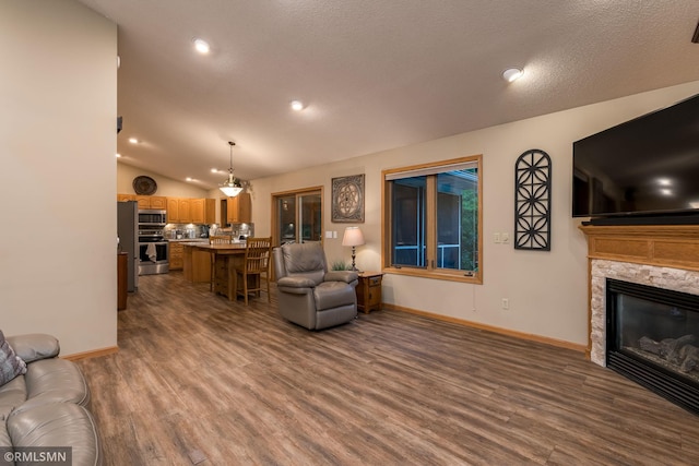 living room featuring a stone fireplace, vaulted ceiling, a textured ceiling, and dark hardwood / wood-style flooring