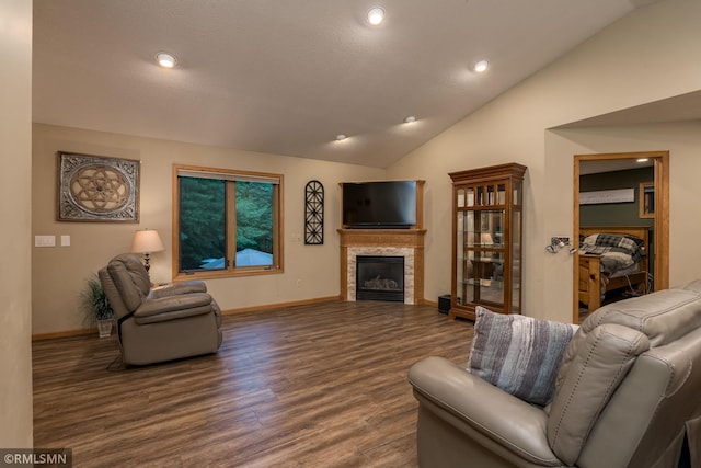 living room featuring vaulted ceiling, dark wood-type flooring, and a stone fireplace