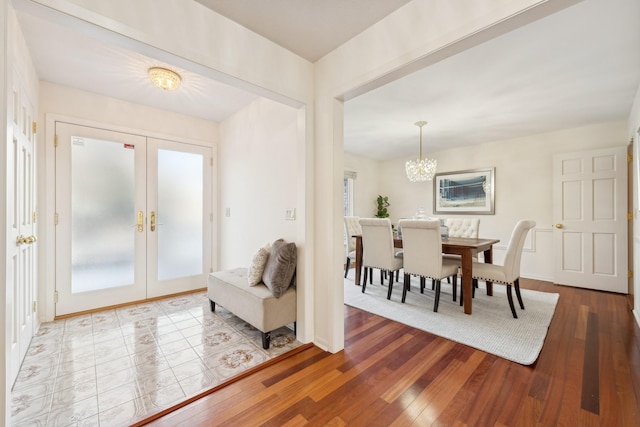 foyer with wood-type flooring, a notable chandelier, and french doors