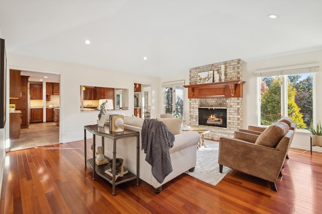 living room with lofted ceiling, hardwood / wood-style floors, and a brick fireplace