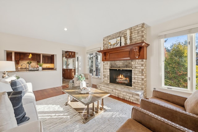 living room with lofted ceiling, a fireplace, light hardwood / wood-style flooring, and a wealth of natural light